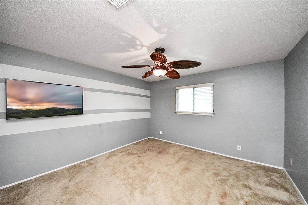 Bedroom 4– Stylish bedroom with an accent striped wall, ceiling fan, and large window offering natural light.
