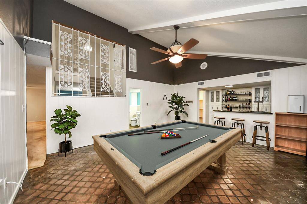 Expansive game room with high vaulted ceilings, exposed beams, and a full bar—perfect for entertaining! Virtual staging used to help visualize the space.