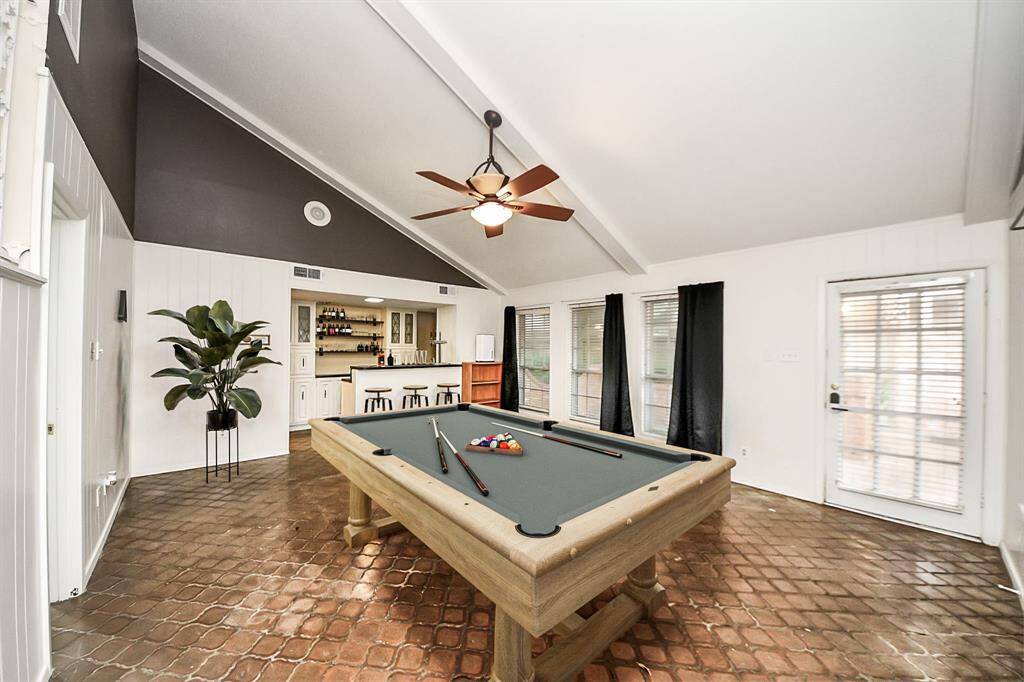 Spacious game room with vaulted ceilings, exposed beams, and a built-in bar, perfect for entertaining, game nights, or creating your dream hangout space Virtual staging used to help visualize the space.