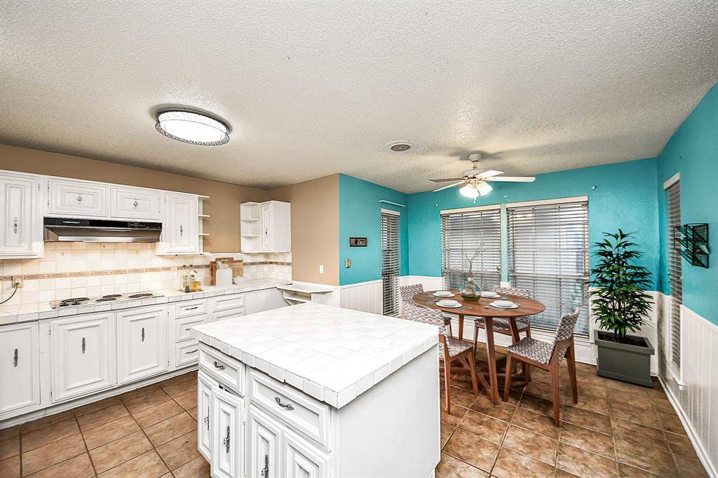 Large kitchen with tiled counters, island, ample cabinet space, and adjoining breakfast area for casual meals. Virtual staging used to help visualize the space.