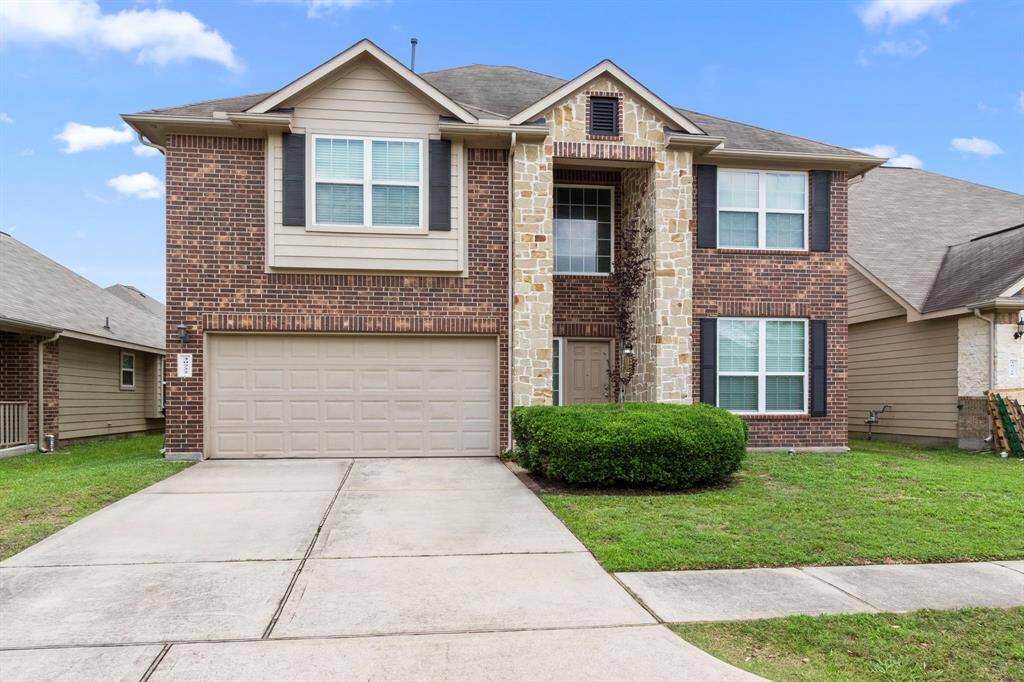 This inviting two-story brick and stone home features a double garage, manicured lawn, and a welcoming entrance with charming architectural details. Ideal for family living.