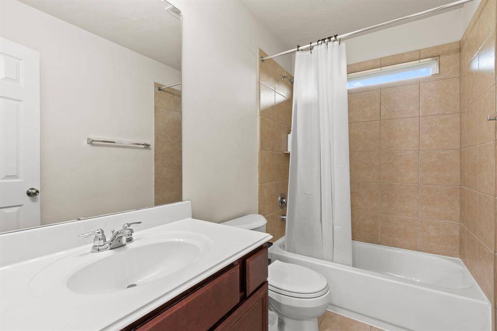 This is a clean, modern bathroom featuring a vanity with a sink, a bathtub with a shower, and neutral tile walls. It's bright and functional, ideal for daily use.