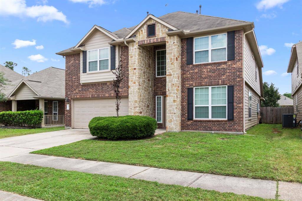 This two-story home features a brick and stone exterior, a double garage, and a neatly maintained front lawn. Ideal for families, it offers ample windows for natural light and a welcoming facade.
