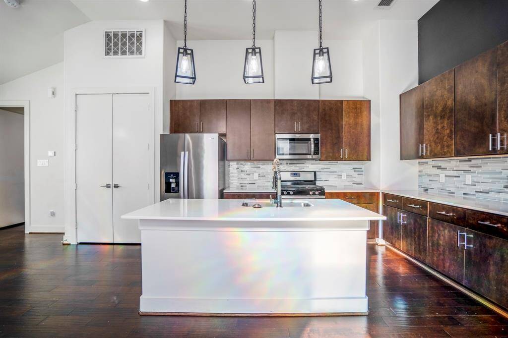 Wide view of kitchen with stainless appliances and modern finishes.