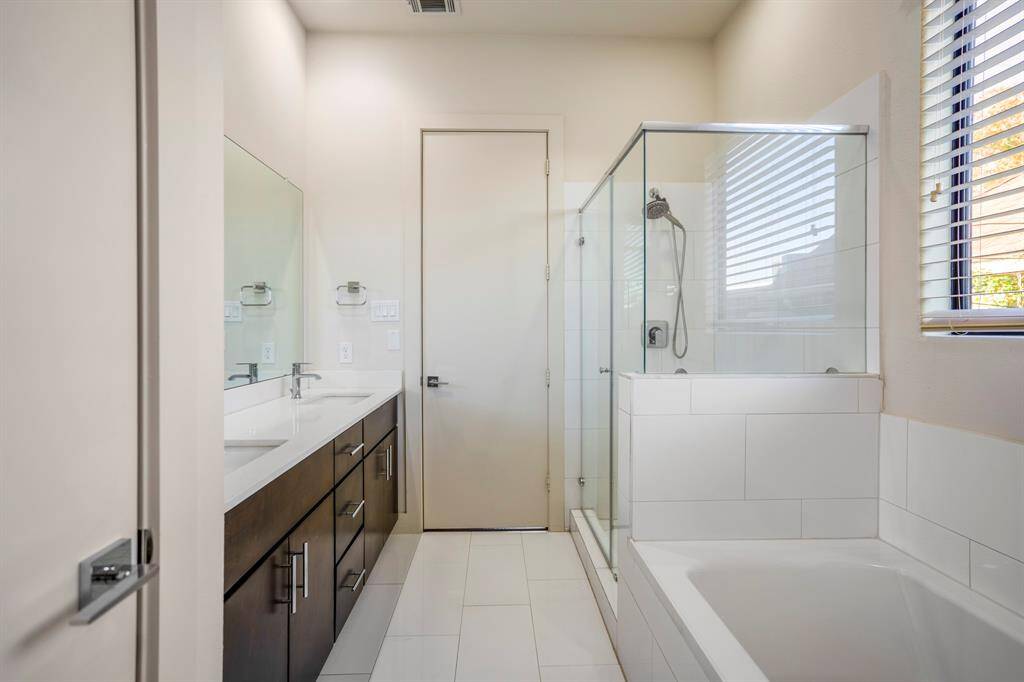 Primary bath features dual sinks, soaking tub, and glass-enclosed shower.