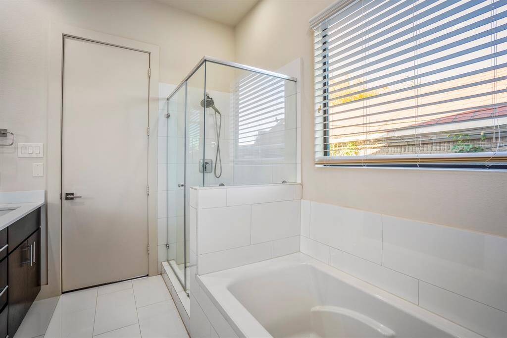 Primary bath features dual sinks, soaking tub, and glass-enclosed shower.