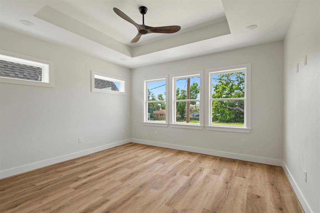 A tranquil retreat, the spacious primary bedroom exudes comfort and relaxation. Large windows frame beautiful outdoor views, while sleek flooring enhances the cozy yet elegant atmosphere. The attached en-suite bathroom features luxurious fixtures, framed mirrors and a spa-like soaking tub, and a walk-in shower.
