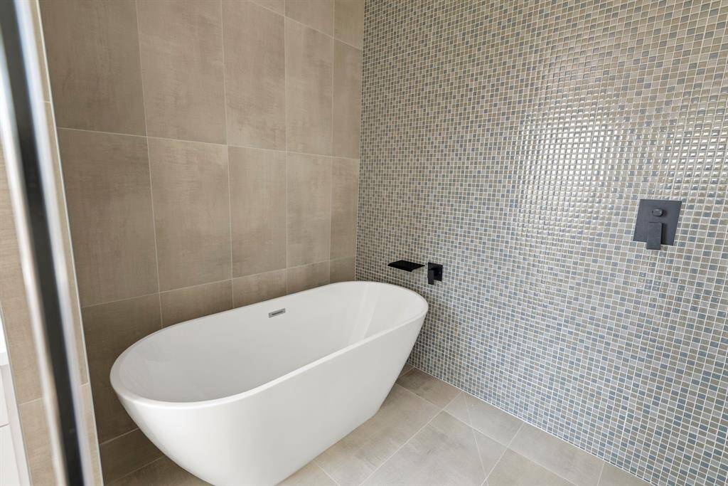 Your daily retreat awaits with a stunning freestanding tub and a sleek glass shower featuring a peaceful rainfall showerhead—pure relaxation.
