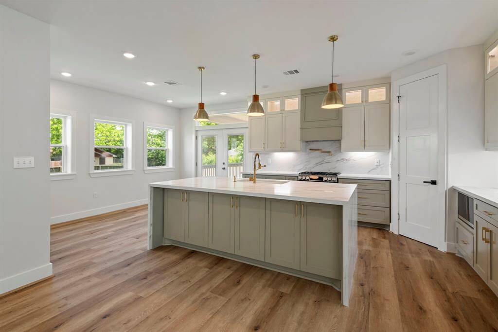 Beautiful light oak floors flow throughout, while custom cabinets with subtle lighting create a warm, welcoming glow.