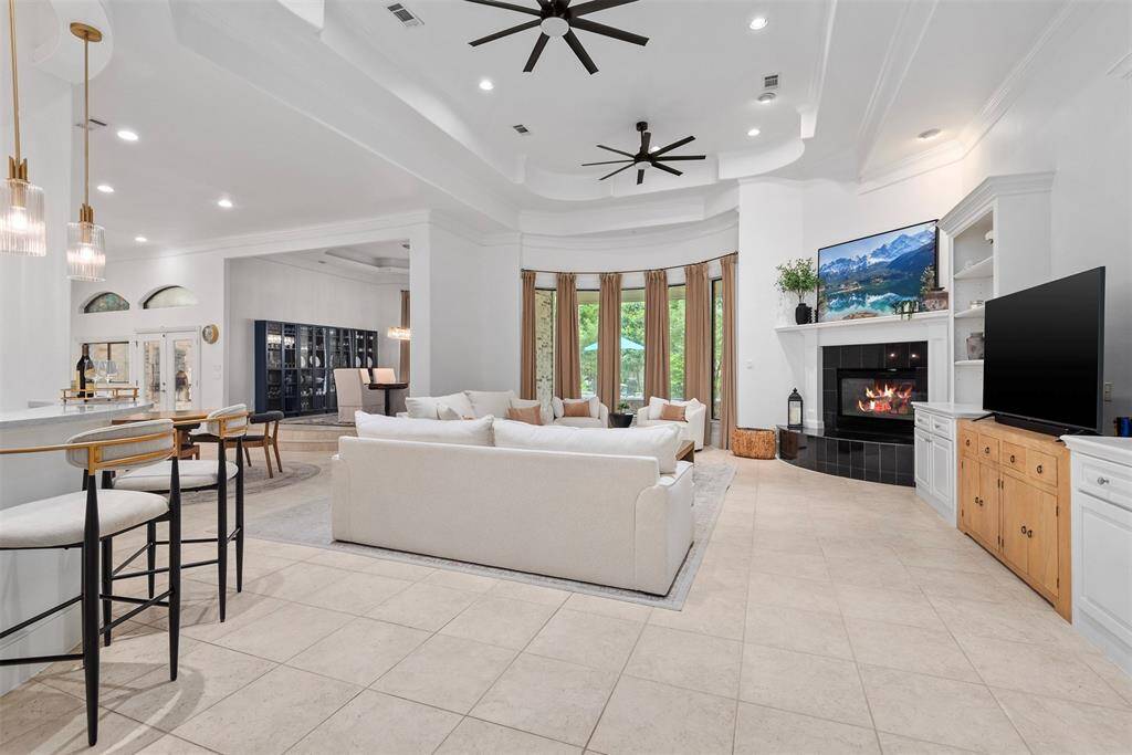 Family room with tall tray ceiling, custom built-ins with a view of the raised formal dining room and the wet bar area to the left.