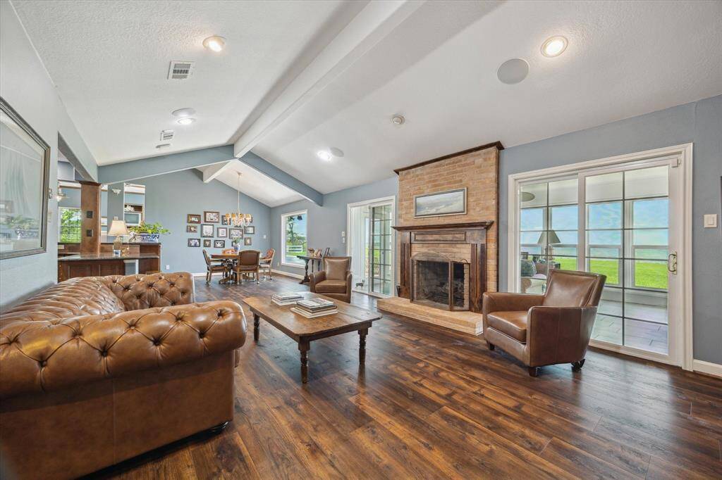 A view from the opposite of the side of the den. The den is open into the breakfast area. The den has a wood burning fireplace, equipped with gas logs that has a brick surround and custom wooden mantle.