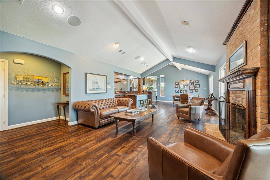 In this view across the den, the arched opening at the left leads to bedrooms 2-4, the second full bathroom and the laundry room. The kitchen and breakfast area are at the opposite end.