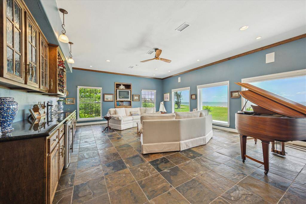 The family room, as seen when entering, features slate tile flooring, high ceiling and a wall of windows.