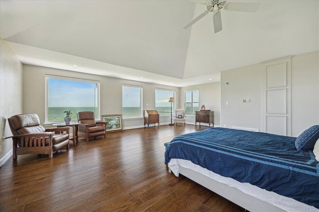 The view when entering the upper level primary suite. The primary suite is at the rear of the home. The location allows unrestricted views of the bay through the triple windows.