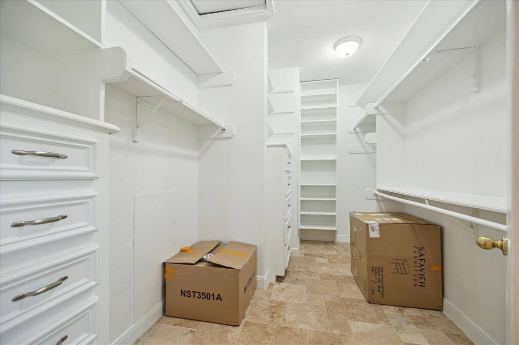 One of the two primary suite walk-in closets. The closets have built-in drawer storage and shelving.