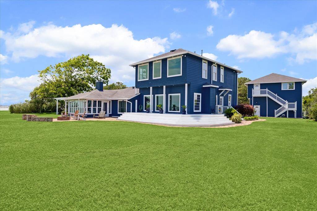 This view of the bay-side elevation shows the wrap-around porch that is accessible from the family room and the detached garage and apartment.