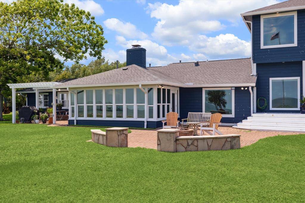 A view of both of the patio areas, the rear elevation of the sunroom and the large windows in the breakfast, family room and upper level primary bedroom.