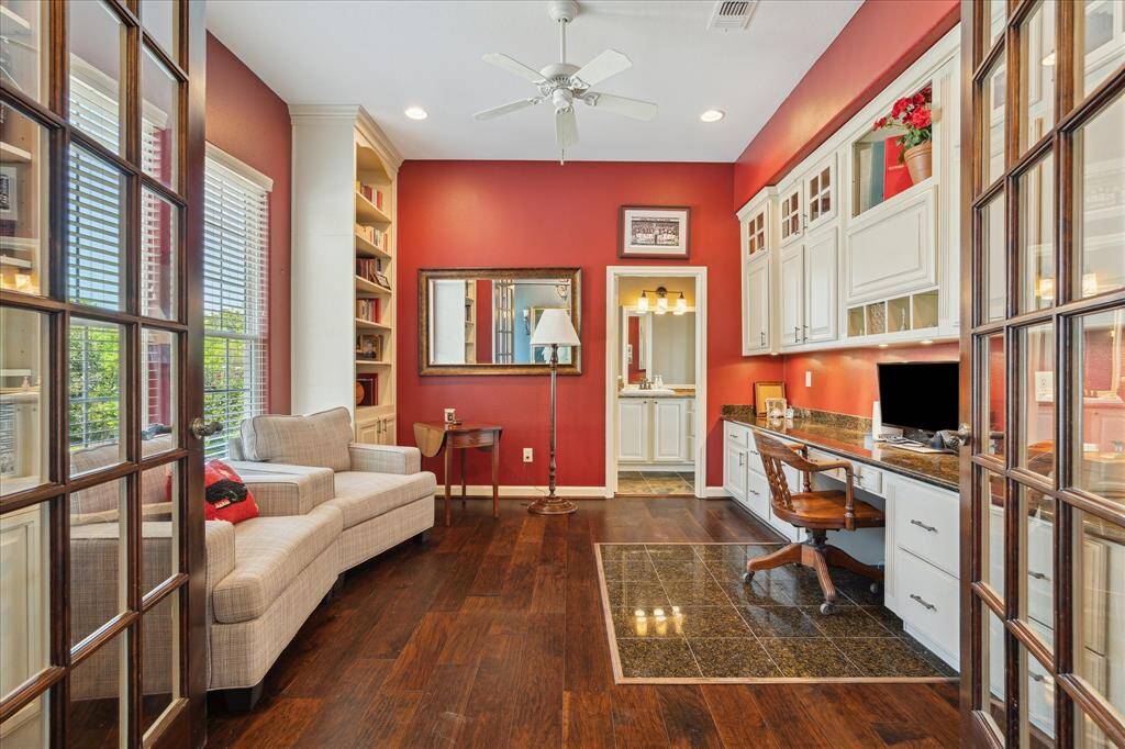The office/study is at the left of the entry. French doors provide access to this room that has a wall of built-in upper cabinet storage, a slab granite surfaced desk area with lower level drawer and cabinet storage. The opposite side of the study has floor to ceiling built-in cabinetry with book shelves with lower level cabinet storage and double windows that overlook the front grounds.
