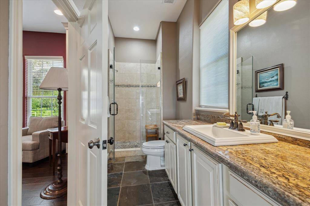 This full bath is accessible directly from the office/study and features an extended vanity with granite top, slate tile floor and shower with tile surround with accent and frameless glass. This bathroom is also directly accessible from the family room.