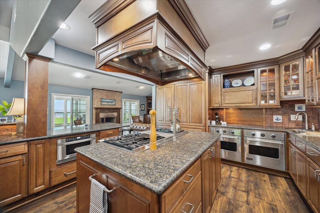 This home features a true "Chef's" kitchen. Dual commercial grade Viking convection gas ovens, an appliance "garage" cabinet, second undermount round sink, undercabinet lighting and built-in steamer. The island is home to a 6-burner commercial grade cooktop with griddle. The commercial style vent hood is housed in cabinetry that matches the cabinetry throughout the kitchen. Recessed lighting and crown molding are other details incorporated into the kitchen.
