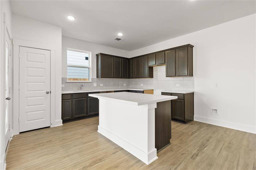 Natural light pours in through large windows, creating a bright and airy atmosphere that makes cooking feel less like a chore and more like a delightful experience. Microwave, Dishwasher, Stovetop range are included, just not pictured.