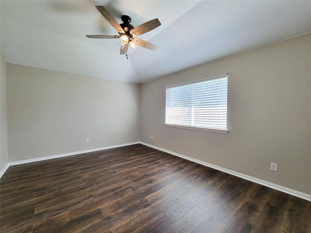 Spacious primary bedroom featuring elegant wood laminate flooring.