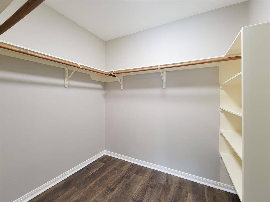Expansive walk-in closet by the primary bath, featuring a convenient built-in shelving unit.