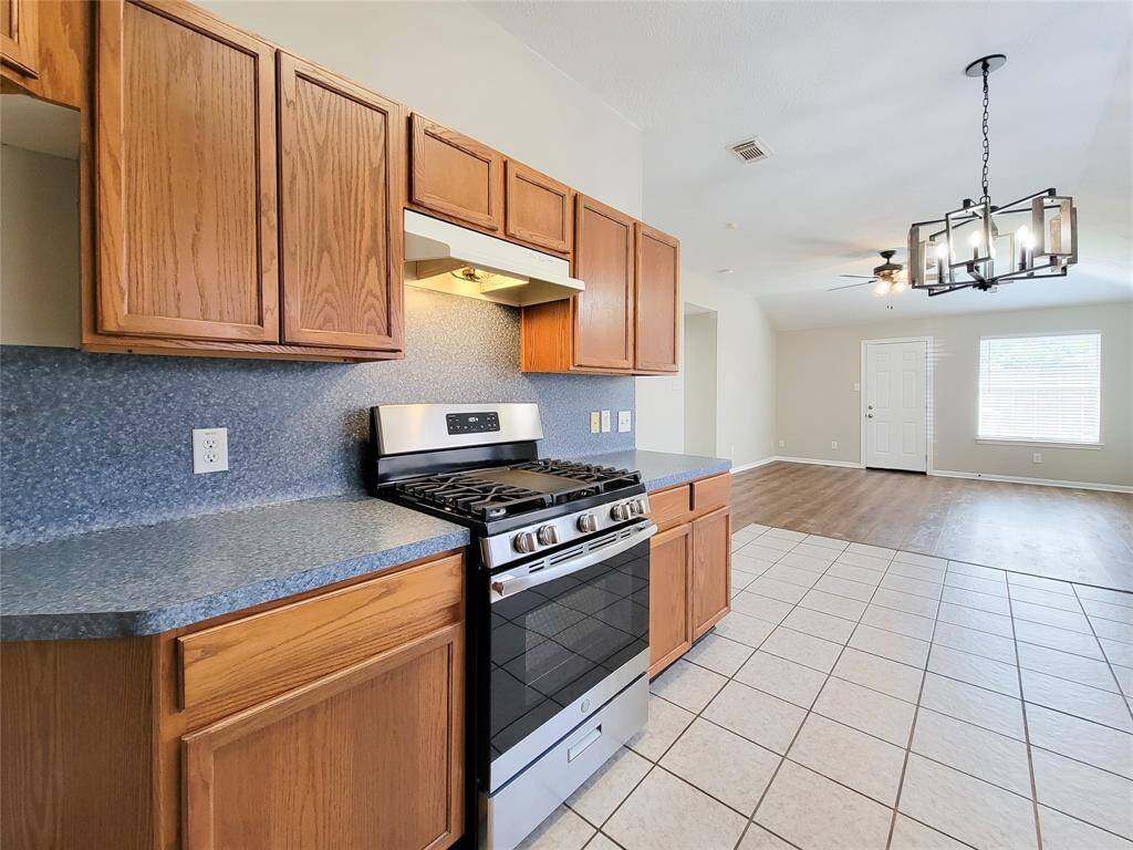 Charming kitchen with elegant wood grain cabinets and a modern gas range/oven.
