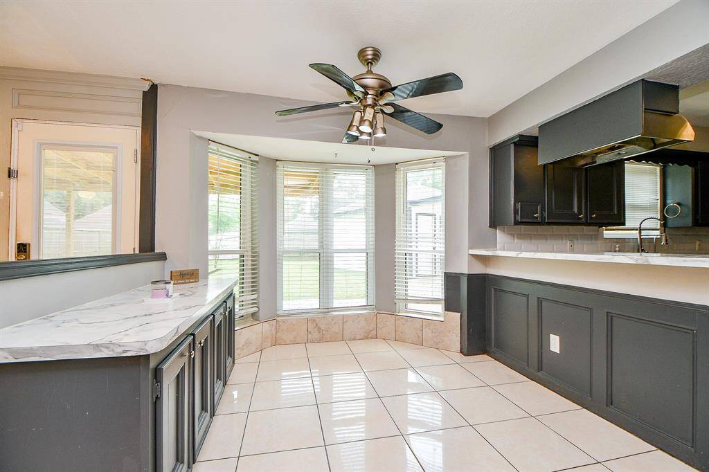 A sleek kitchen area is visible, featuring white cabinetry and a spacious countertop, maintaining the modern and minimalist theme. Recessed lighting in the ceiling further enhances the overall brightness of the room.