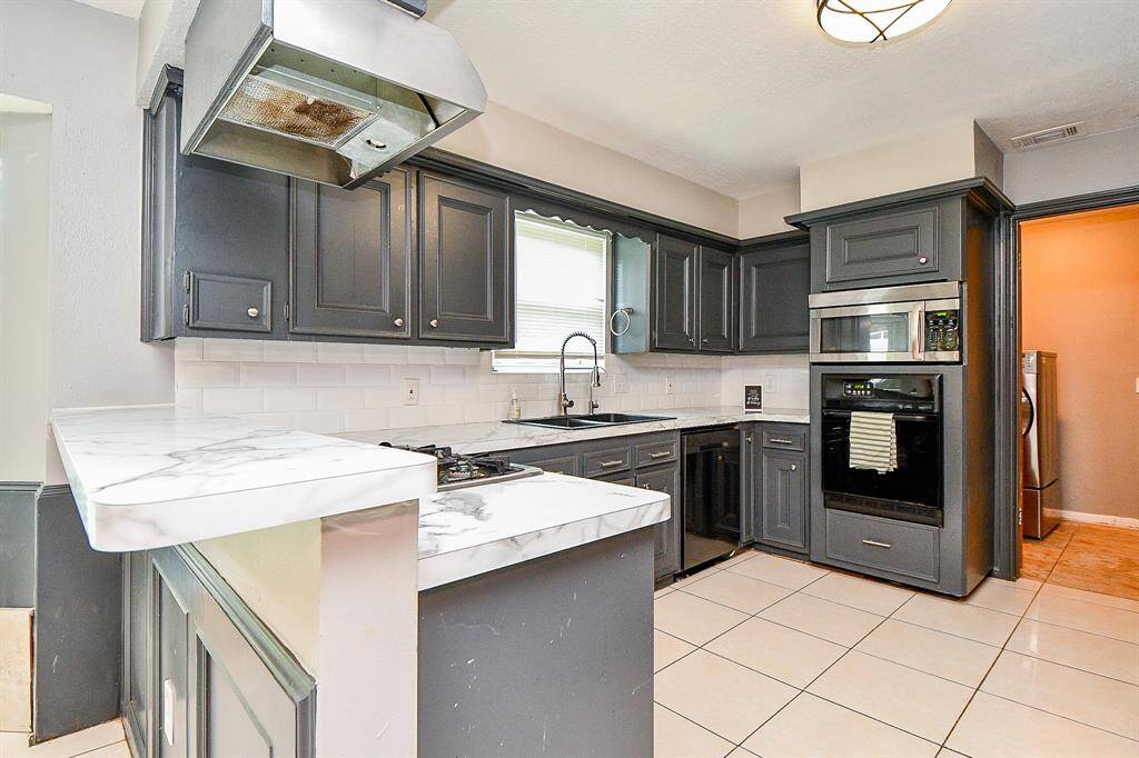 A strategically placed sink beneath a large window provides natural light and a pleasant view while you prep and clean. The gleaming white tile backsplash enhances the brightness, making the space feel fresh and welcoming.