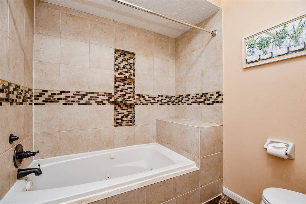 A pristine white bathtub sits elegantly against a tiled wall, equipped with modern black fixtures.
