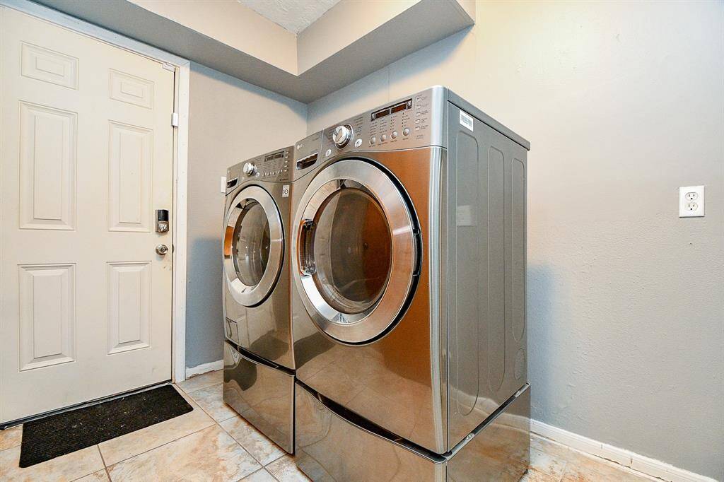 A modern laundry room equipped with two stainless steel front-loading machines—a washer and a dryer—placed side by side for convenience.