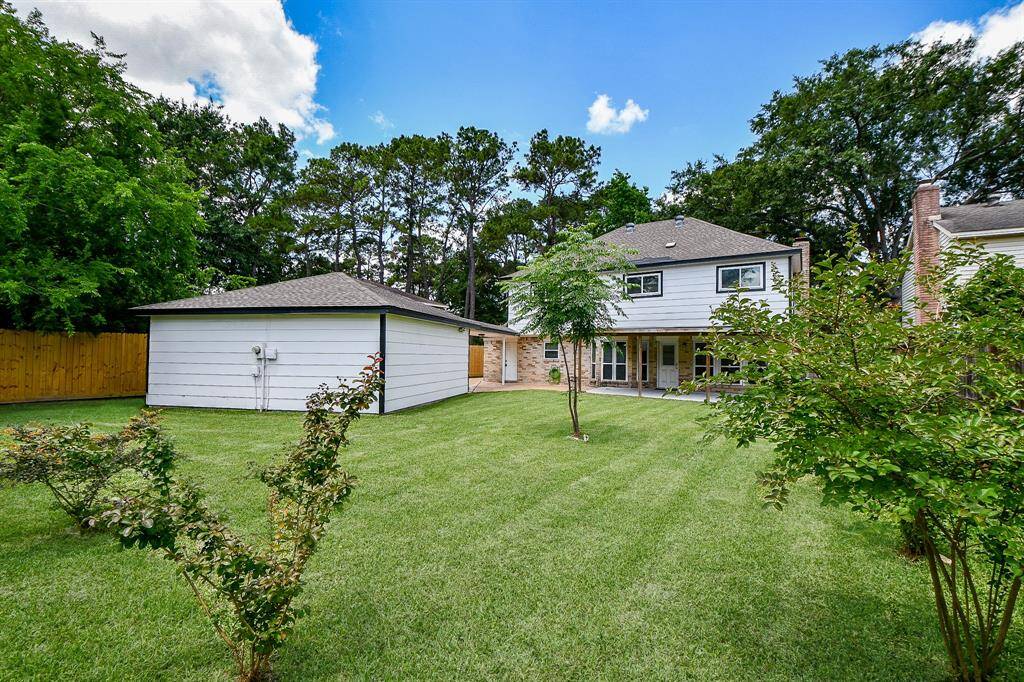 a well-maintained grassy lawn stretches across the yard, bordered by a classic wooden fence that provides privacy and security.