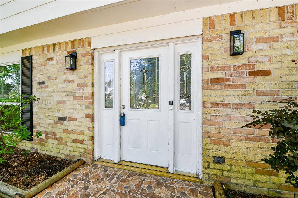 This home's front entrance exudes elegance and warmth, creating a welcoming first impression. The focal point is a striking white double door with glass panels in the upper half, allowing natural light to filter through while maintaining privacy.