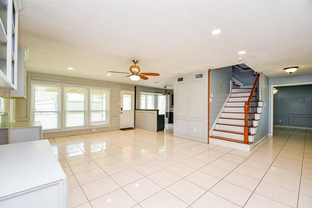 A spacious and modern home interior with an open floor plan that emphasizes brightness and functionality. The room is illuminated by natural light streaming in through large windows on the left side, which frame an inviting view of the outdoors.