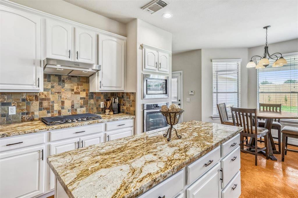 The kitchen is further enhanced by a gas range, complete with a sleek vent hood above, adding both style and functionality to the cooking space.