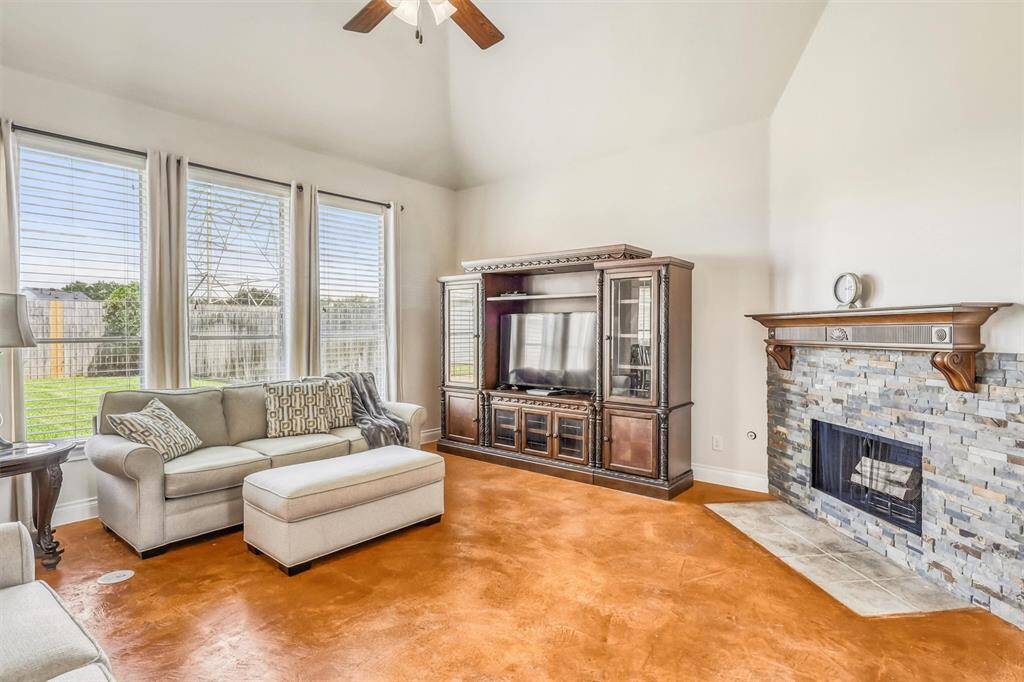Welcome to this expansive and inviting living room, where three floor-to-ceiling windows line the back wall, flooding the space with natural light and creating an airy, open atmosphere.