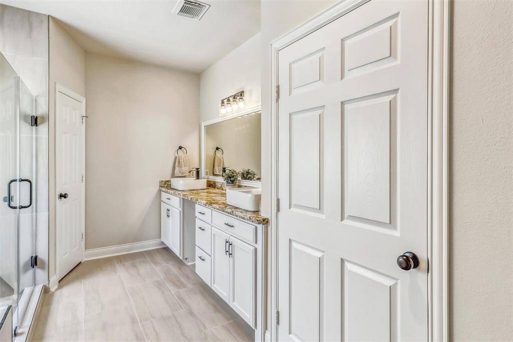 Welcome to your spa-inspired ensuite, beautifully remodeled to blend luxury with thoughtful design. Every detail has been carefully curated to create a serene, sophisticated retreat. The large vanity features painted cabinets, elegant granite countertops, and two striking vessel sinks.