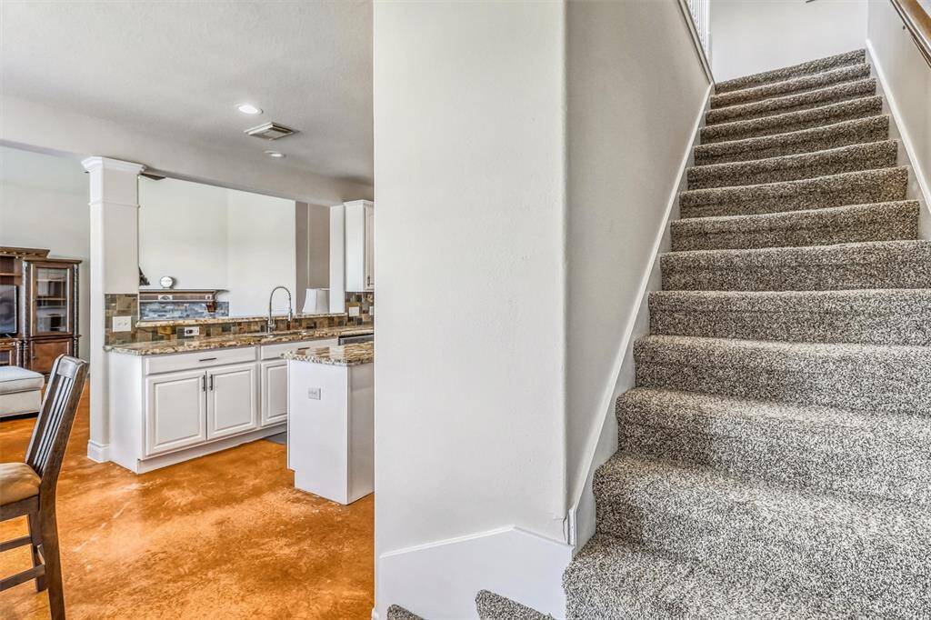 Ascend the carpeted staircase to the second level, where you'll find a spacious game room and the home's secondary bedrooms, offering plenty of space for relaxation and versatility.