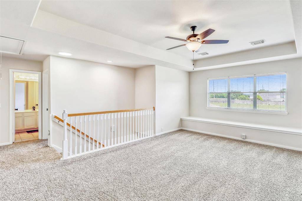 Welcome to your upstairs game room, where the eye is drawn to the elegant tray ceiling and a striking wall of windows, featuring a bench seat that spans the entire back wall—perfect for enjoying views or relaxing in natural light.