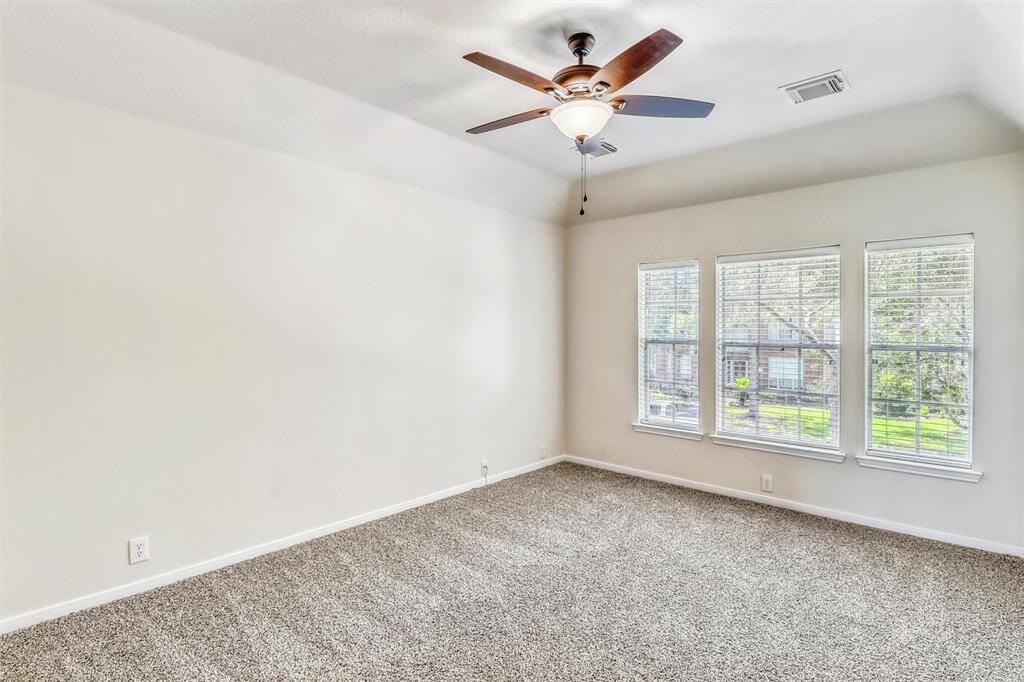 This secondary bedroom blends comfort and style, with plush carpeting, a high ceiling, and elegant decorator paint. Additional highlights include a spacious closet, a ceiling fan, and three bright windows that flood the room with natural light.