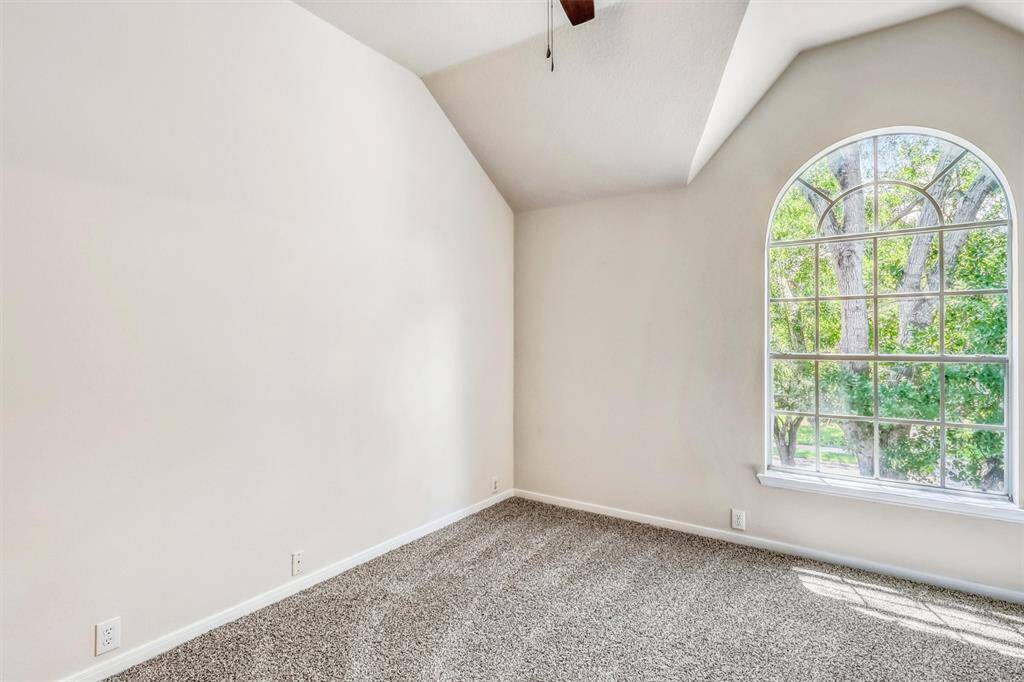 The second guest bedroom continues the home’s thoughtful design, featuring sophisticated decorator paint and plush carpeting. A roomy closet, a bright arched window, and a high ceiling that adds dimension create a comfortable and stylish retreat.