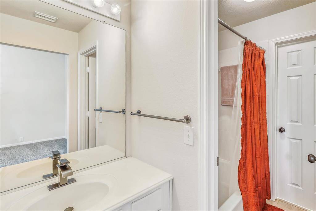 The connected vanity features crisp white cabinetry and countertops, complemented by an updated faucet for a clean, refreshed look. The bathroom includes a tub/shower combination, offering versatility for both quick showers and relaxing baths.