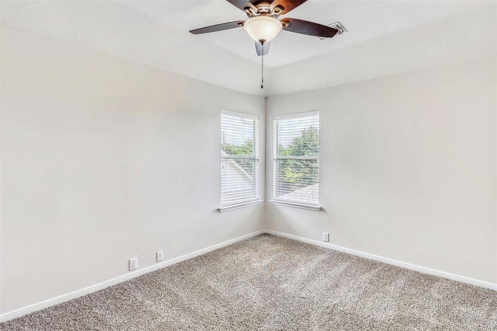 Guest bedroom three is generously sized and thoughtfully designed, featuring sophisticated decorator paint, plush carpeting, and a ceiling fan. Two windows brighten the space and enhance its welcoming charm.