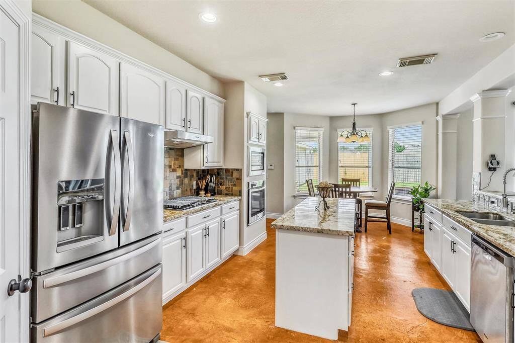 Just beyond the entryway, the heart of the home awaits—this spacious, open-concept kitchen is perfect for seamless entertaining. Recently painted cabinetry, luxurious granite countertops, and a stylish backsplash come together to create a functional and beautiful space.