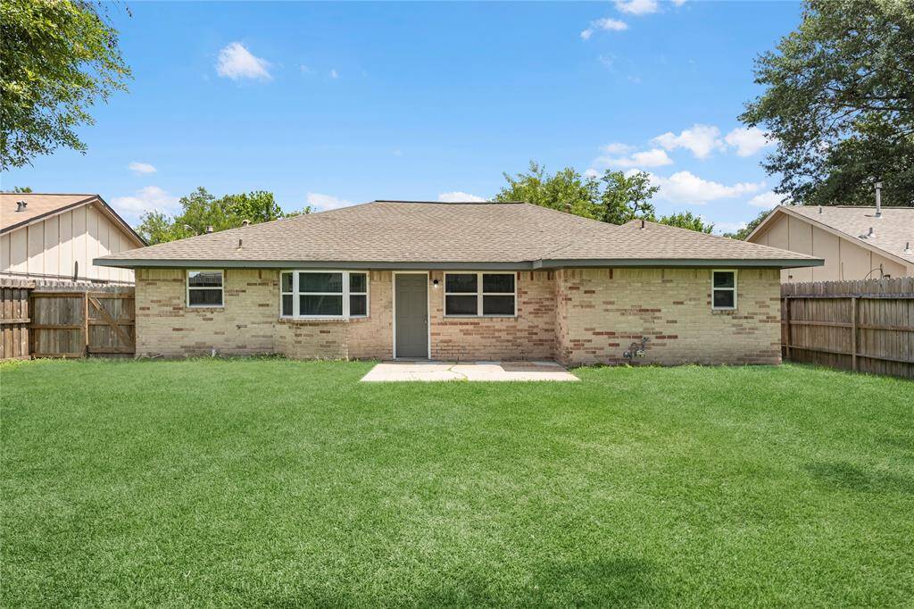 Spacious backyard with a brick home, ready for new owners.