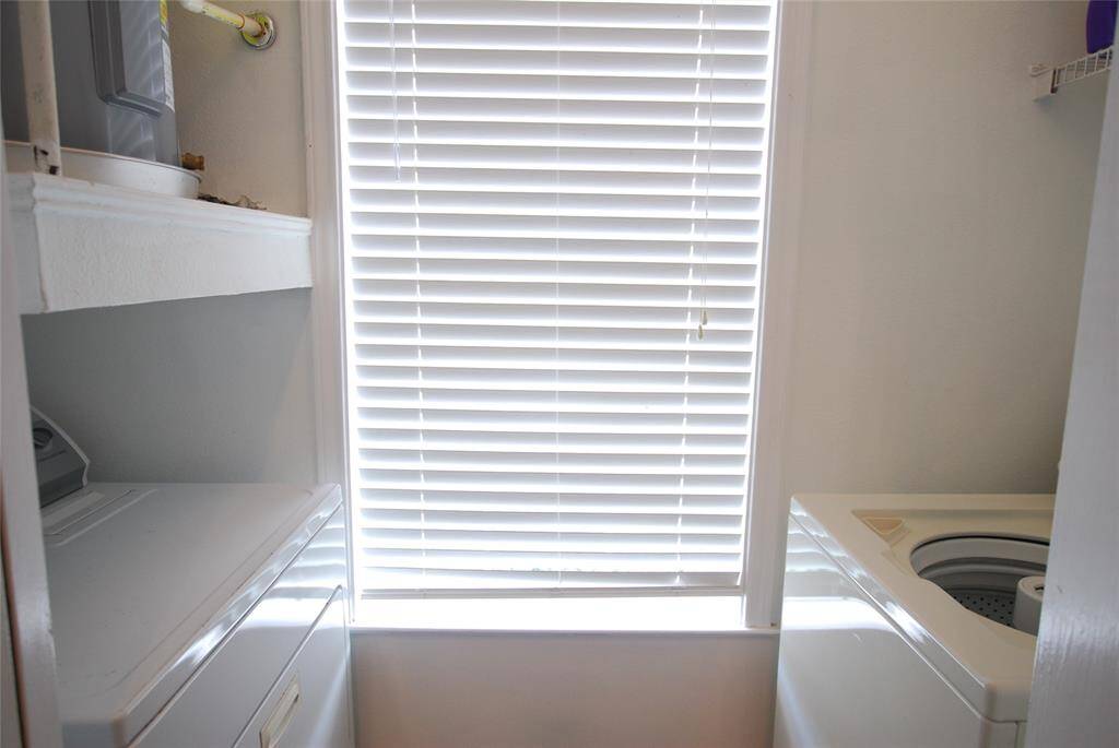 Utility room with electric washer and dryer included in back of kitchen.