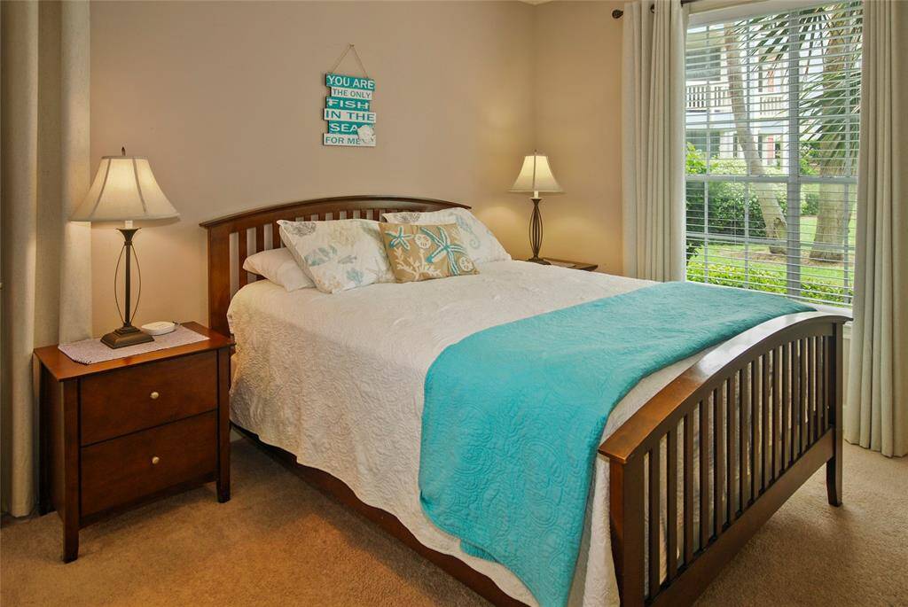 Primary bedroom has view of pool and green space.