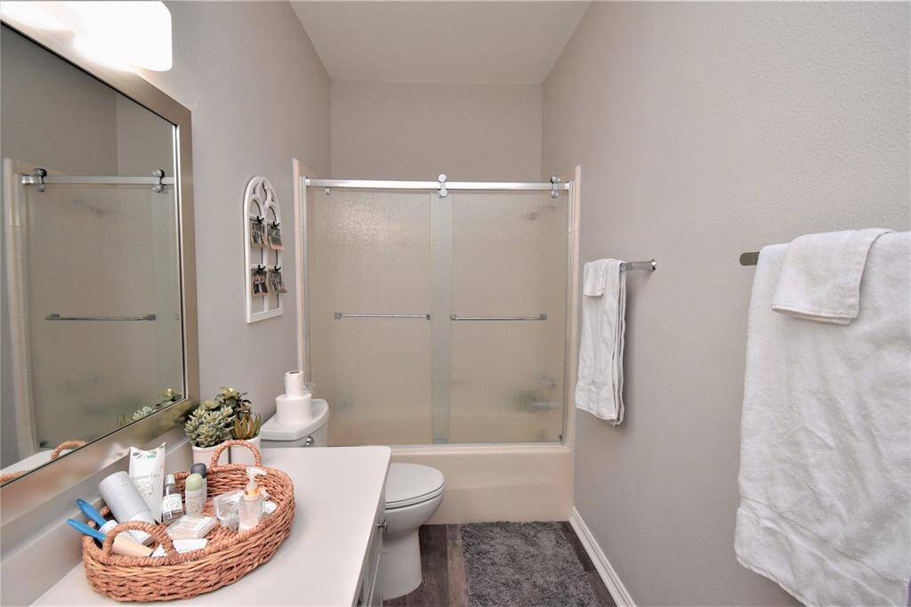 Long layout bathroom with frosted glass sliding door and bathtub.
