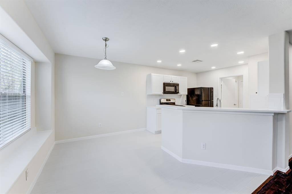 Dining Area & Kitchen ViewBright and open dining area with bay window seating, flowing seamlessly into the updated kitchen with modern finishes and recessed lighting.